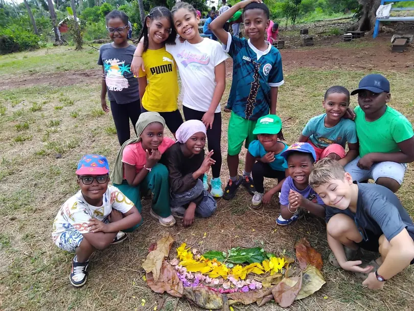 Élèves souriants autour d'une composition de fleurs et de feuilles en pleine nature